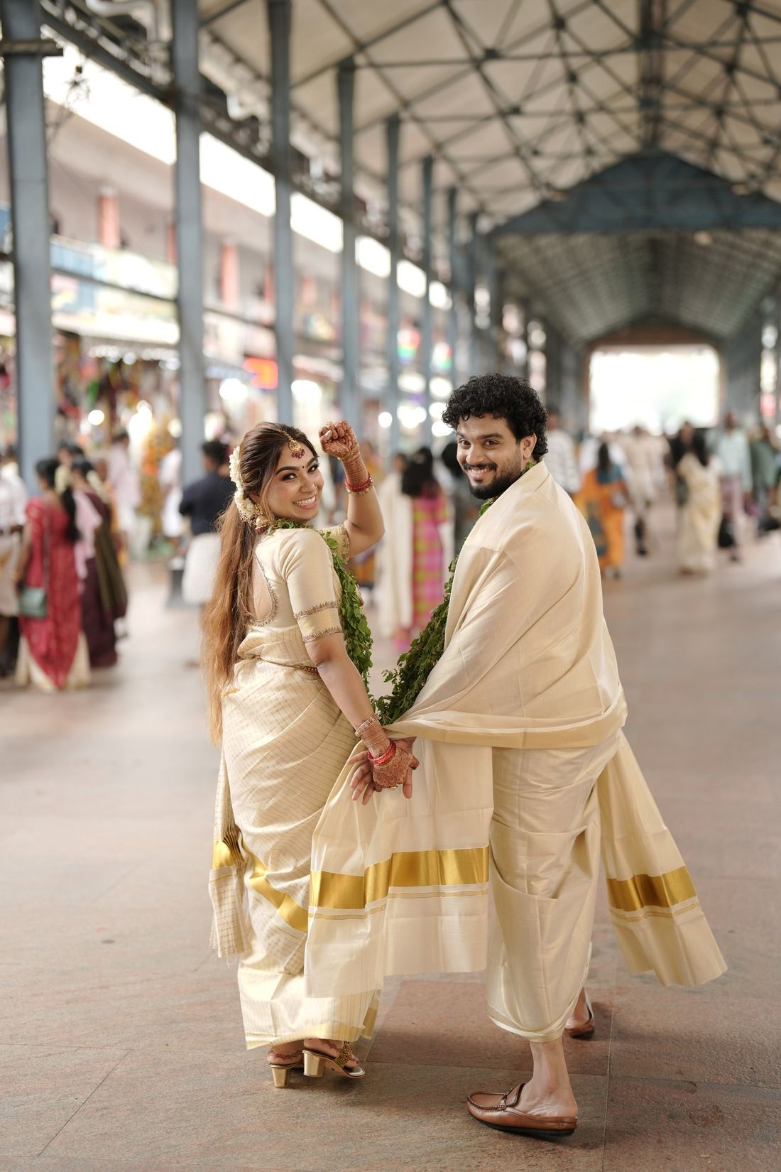 Bride and groom walking hand in hand in traditional Kerala wedding attire